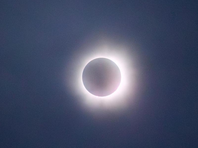 的 image captures a solar eclipse in its totality phase, where the moon completely covers the sun, leaving only the bright corona visible as a glowing ring around the darkened disk. 的 sky appears dark, adding to the dramatic effect of the eclipse. 软, glowing light of the corona creates a striking contrast against the shadowed moon, making this a captivating depiction of a natural celestial event.