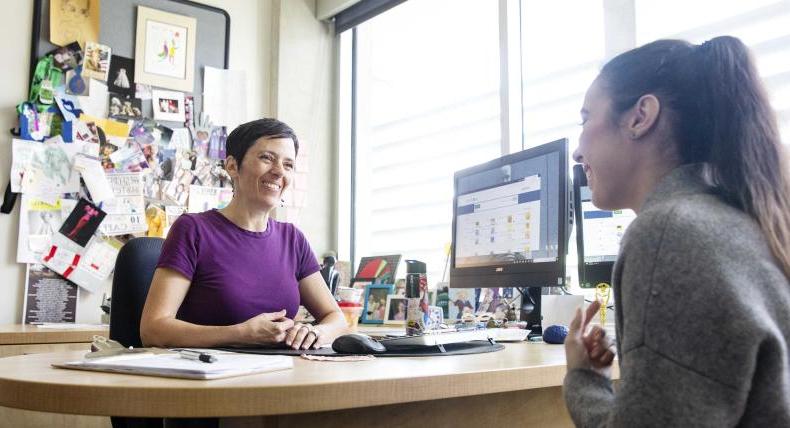 Staff member advises student in university office.