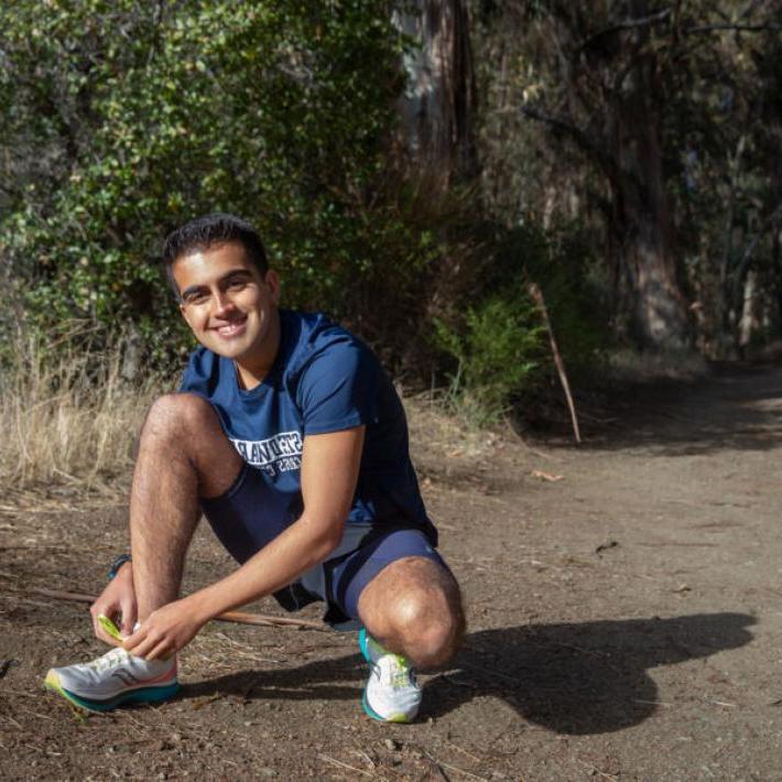 Arrian Ebrahimi tying his shoe on a running trail 