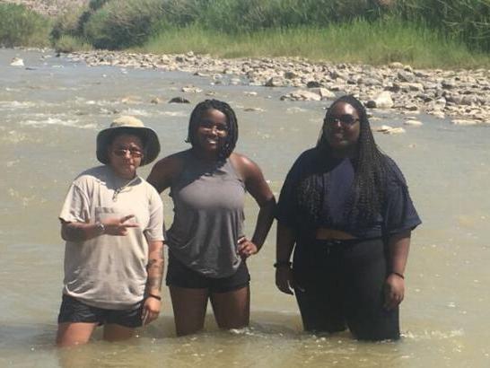 Three students knee-deep in a river