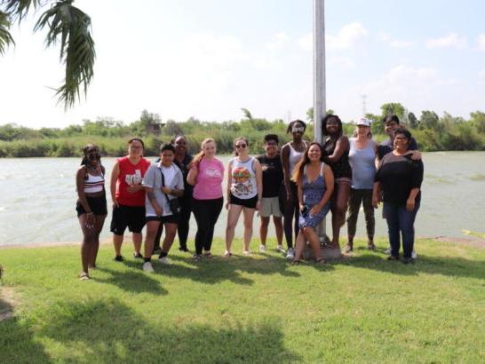 A large group of students poses in front of the river