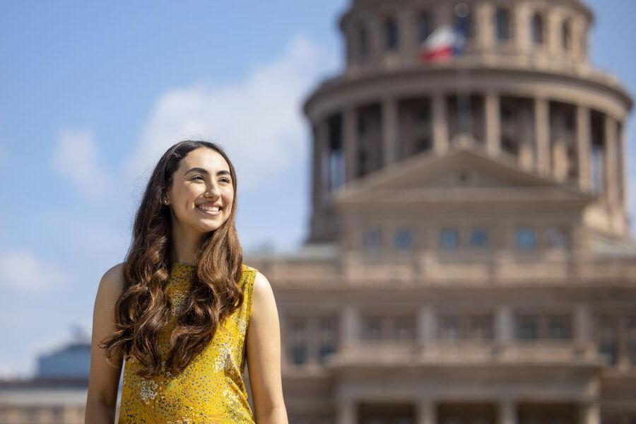 Michelle Flores stands outside of the Texas State Capitol with the building in the background.